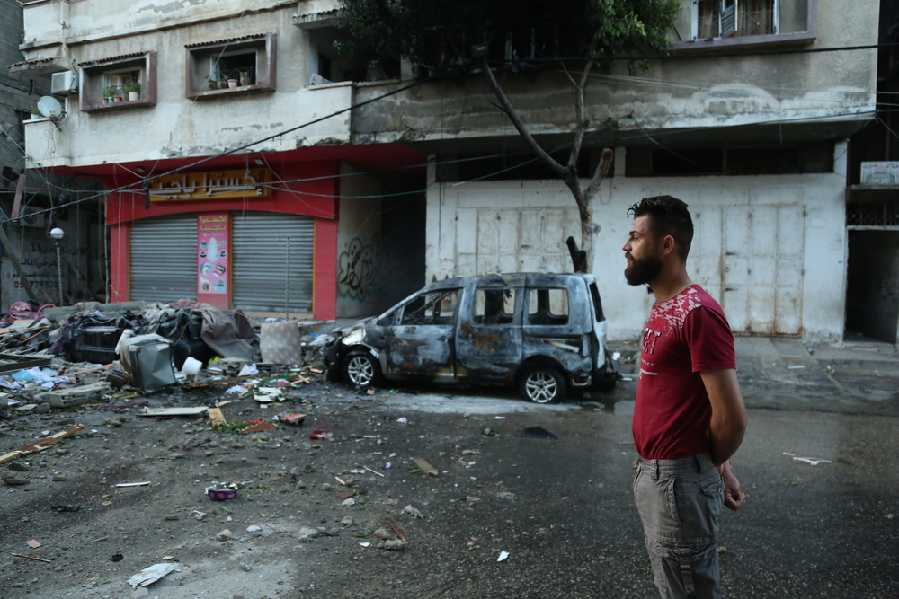 Homem palestino em pé nas ruas de Gaza, após intenso bombardeio